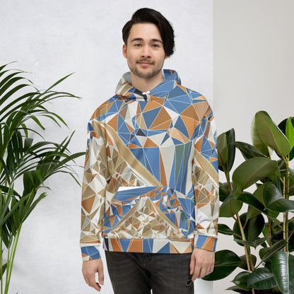 Man wearing a geometric patterned hoodie standing between two plants against a white wall.