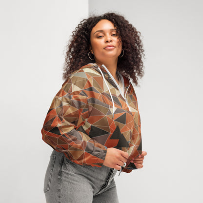 Woman wearing a cropped multicolor geometric patterned windbreaker jacket against a plain background